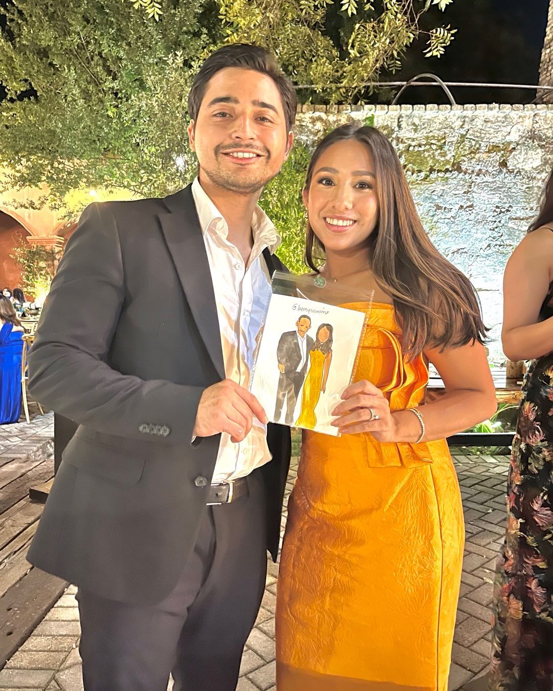 Pareja de novios sosteniendo su retrato pintado en la boda
