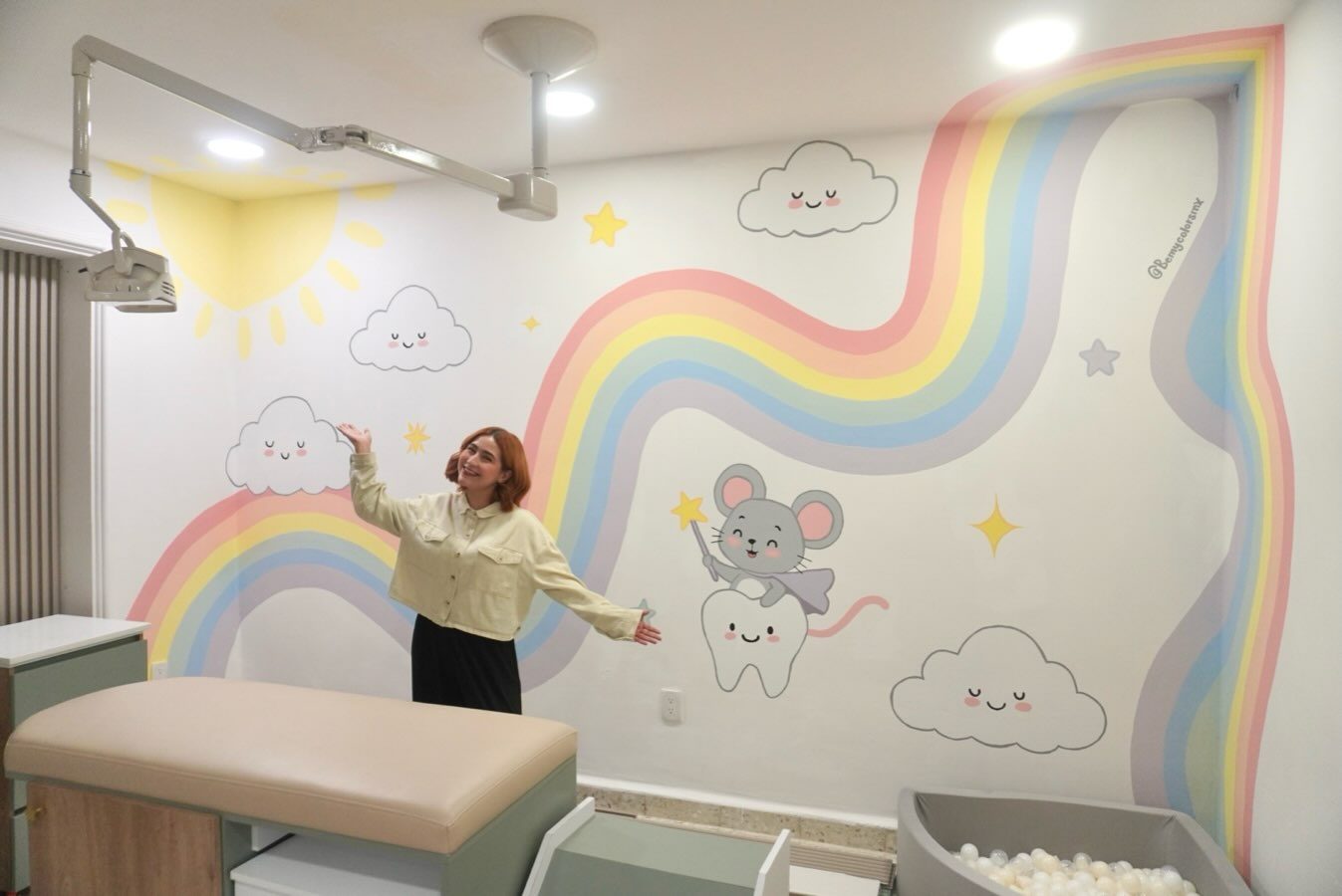 Mural infantil con arcoíris y nubes en un consultorio